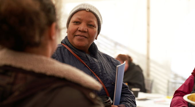 Woman wearing a white hat, smiling at another woman