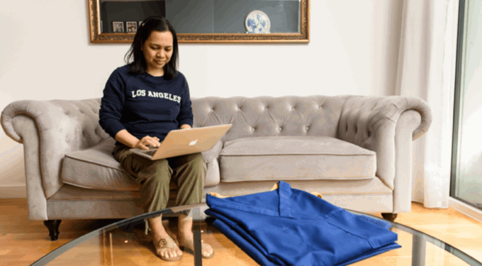 Woman sitting on a grey sofa while using her laptop