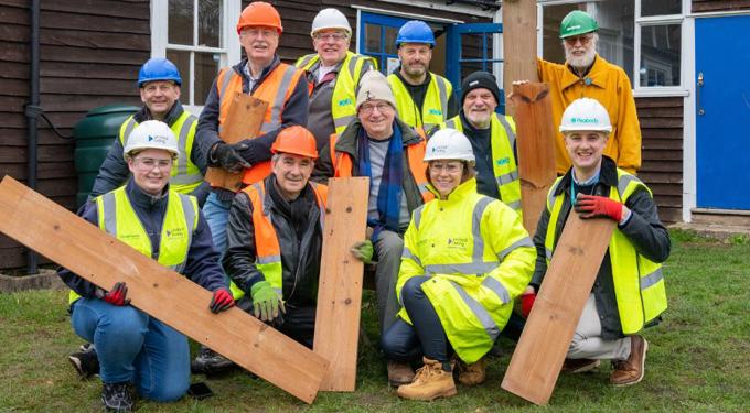 Group of people wearing hard hats and holding wood