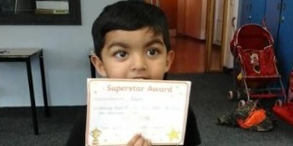 Young boy holding certificate towards the camera