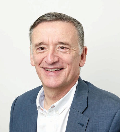 Headshot of a man in a grey suit, smiling