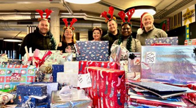 People standing behind piles of wrapped presents