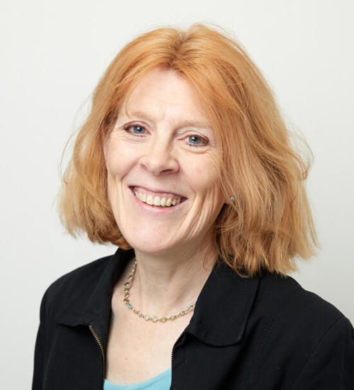 Headshot of a woman in a black jumper, smiling