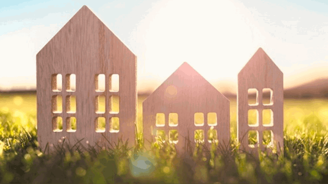 Three wooden two dimensional houses on grass