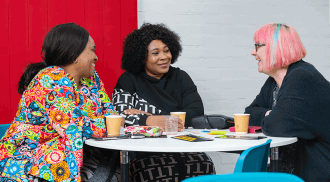 Three women sitting at a table, talking