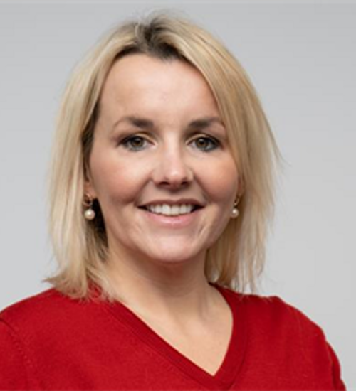 Headshot of a woman in a red top, smiling